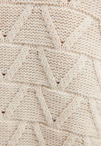 Tessuto a maglia color crema con un motivo testurizzato di triangoli e forme a diamante sollevati. Materiale morbido simile alla lana con punti visibili.