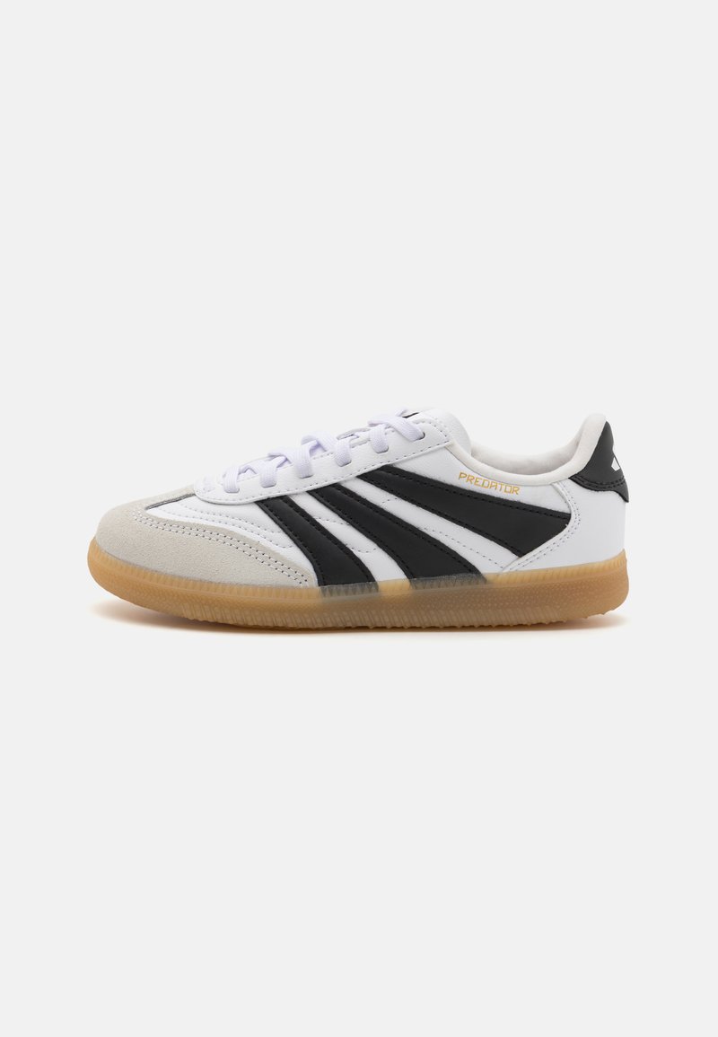 Scarpa sportiva bianca con strisce nere, tomaia in suede e materiale sintetico, suola in gomma, punta rotonda e chiusura con lacci. Marchio dorato "Predator".