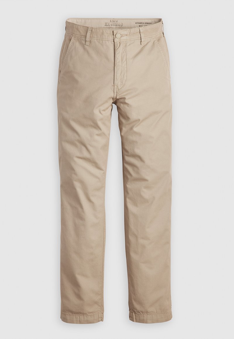 Chinos beiges avec une coupe droite, en coton, dotés d'une fermeture à bouton et à glissière, d'anses de ceinture et de poches latérales. Texture lisse.