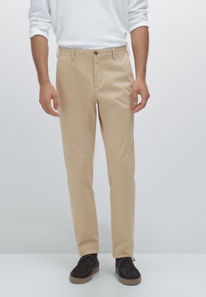 Beige chinos with a straight leg design, single front button, and side pockets. Smooth fabric with a clean, minimalist appearance.