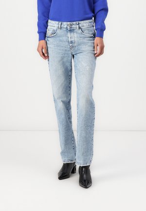 Light-wash denim jeans with a relaxed fit, straight leg, and subtle distressing details at the front. Paired with black heeled boots.