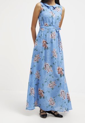 Modré maxi šaty bez rukávů s růžovým květinovým potiskem, peter pan límeček, zavazování v pase, nošeny s černými baletními balerínami.