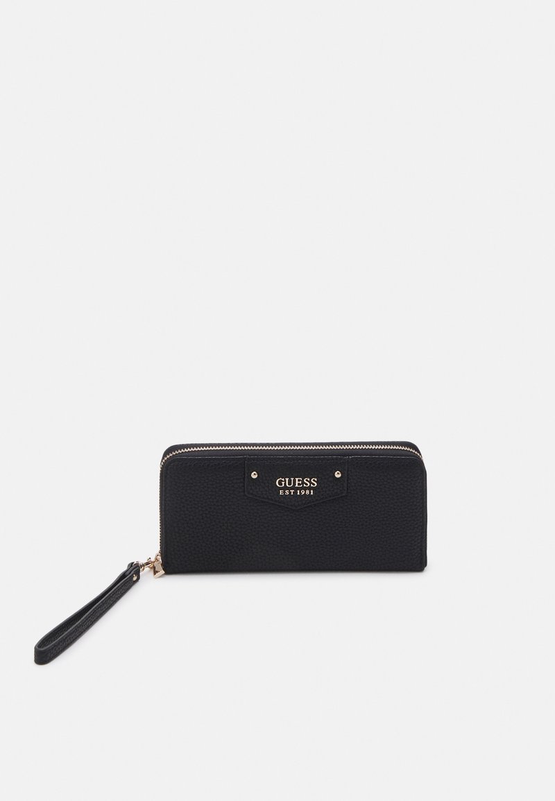 Black textured wallet with gold hardware, featuring a zip closure and a detachable wrist strap. "GUESS EST 1981" logo prominently displayed.
