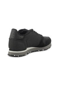 Sneaker nera con una combinazione di materiali in mesh e suede. Presenta un tallone testurizzato, una suola grigia con dettagli a macchie e lacci piatti.