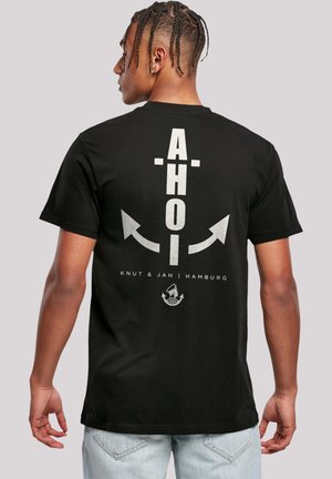 Zwart katoenen t-shirt met zilveren grafische tekst "AHOI" en een ankerontwerp op de achterkant; korte mouwen en een standaard pasvorm.