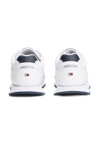 Baskets blanches avec une tige synthétique lisse, des accents bleu marine, une pointe arrondie et une semelle texturée. Présente le logo de la marque près du talon.