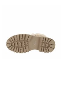 Suela de goma color crema con surcos y estrías profundas para una mejor tracción. Presenta un detalle de marca en el centro y una forma de punta redonda.