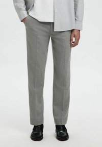 Pantaloni grigi chiari, testurizzati, con una vestibilità dritta, caratterizzati da una finitura liscia e linee pulite. Abbinati a scarpe nere per un contrasto.