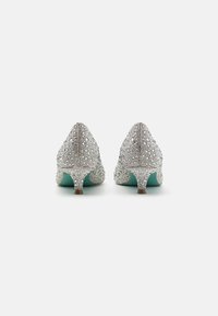 Zapatos de tacón alto adornados en plata con punta afilada, que presentan una textura similar a un cristal y una plantilla de color verde menta. Tacones pequeños y delgados.