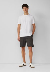 White short-sleeve t-shirt, dark gray shorts, and white sneakers with black accents. Casual outfit for warm weather.