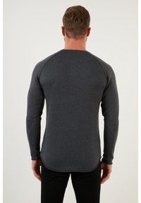 Cămașă gri cu mânecă lungă, cu textură ribbed și mâneci raglan. Are un tiv rotunjit și un design minimalist pentru versatilitate.