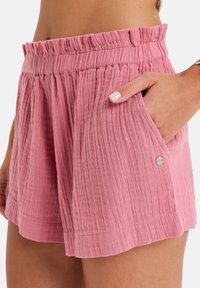 Rosa bomullsshorts med en strukturerad, plisserad design, elastisk midja och sidofickor. Har en liten metall detalj på fickan.