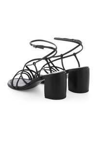 Schwarze Sandalen mit Absatz und strappy Design. Sie besitzen einen Blockabsatz und dünne Riemen, die sich ineinander verhaken und eine moderne Silhouette bieten.