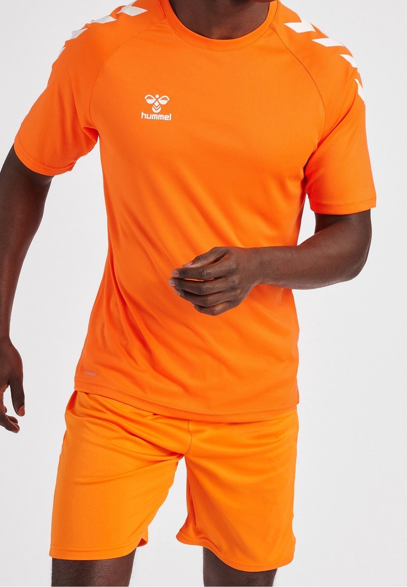 Camiseta y pantalones cortos deportivos naranjas con logo, de manga corta y detalles en diseño zigzag en los hombros. Tela suave que absorbe la humedad.