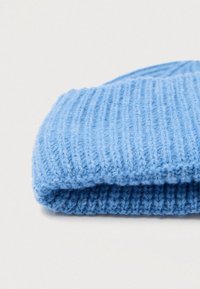 Világoskék kötött sapka bordázott mintával, visszahajtott szegéllyel és puha, bolyhos fonállal, alkalmi viselethez megfelelő.