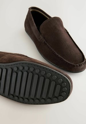 Bruine suède instappers met een gemêleerd bovenwerk, ronde neus en rubberen zool met cirkel- en streeppatronen voor grip.