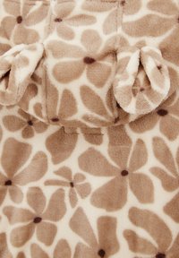 Giraffe-patroon pluche stof in beige en bruin met een zachte textuur. Heeft ronde oren en bloemblaadjes in donkerdere tinten.