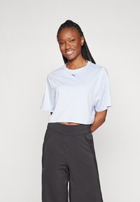 Ljusblå kortärmad t-shirt med korta ärmar, försedd med en liten marinblå logotyp på bröstet, ihop med svarta vida sportbyxor.