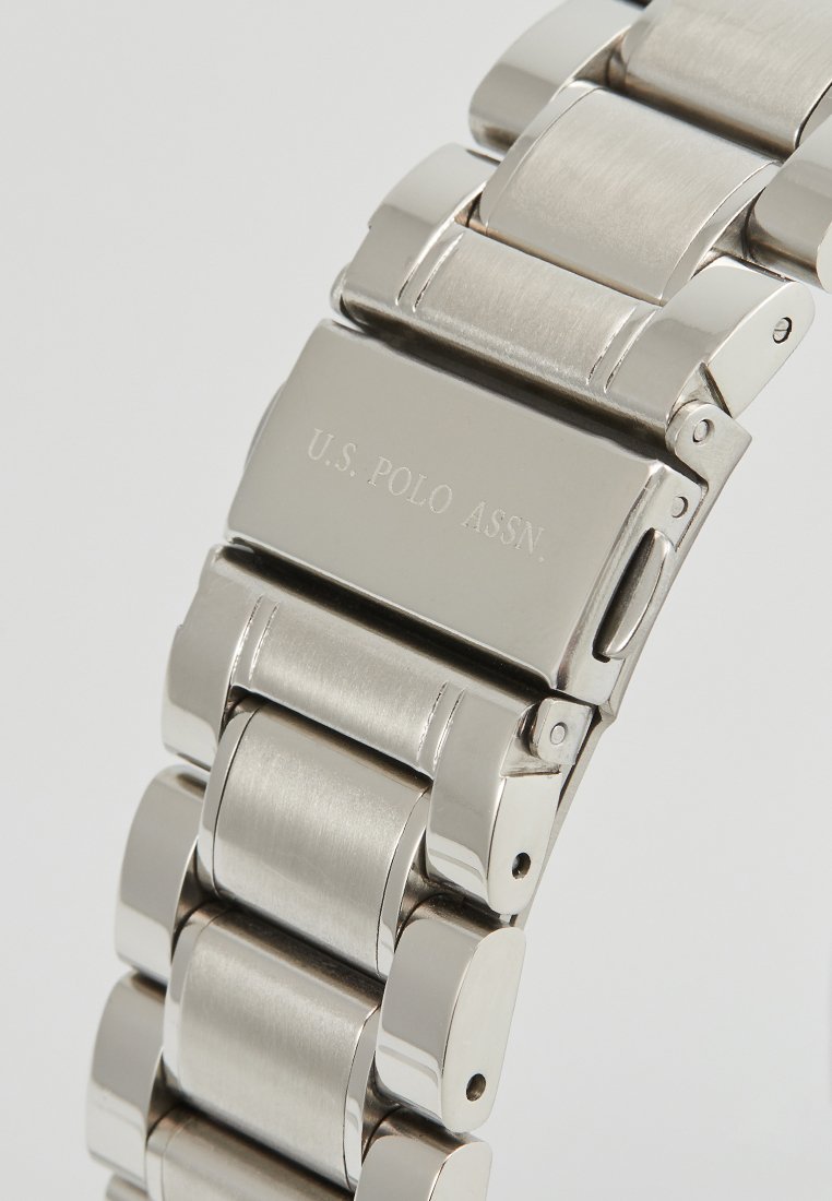 Bracelet de montre en acier inoxydable avec finitions polies et brossées, doté d'un fermoir gravé "U.S. POLO ASSN." Les maillons ont une forme arrondie.