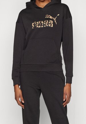 Sweat à capuche noir porté avec un pantalon assorti, avec une poche kangourou à l'avant et le logo Puma en imprimé léopard sur la poitrine.