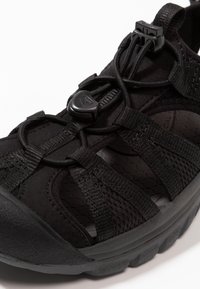 Black outdoor sandal featuring a textured rubber sole, synthetic upper, adjustable laces, and open design for ventilation.