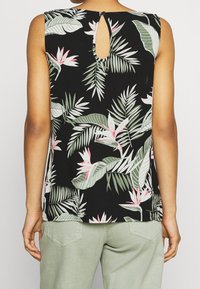 Top senza maniche di colore nero con una stampa botanica di foglie verdi e fiori rosa. Presenta un dettaglio a chiave sulla parte posteriore e una vestibilità rilassata.