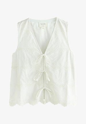 Hvid ærmeløs vest med bølget kant, der har intrikate broderede skaldmønstre og en snøre foran. Blødt tekstureret stof.