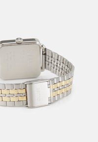 Montre-bracelet en métal bicolore argent et or avec un boîtier carré, un dos texturé et un fermoir gravé "CLUSE."
