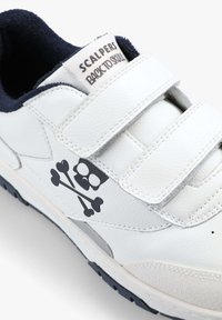 Weiße Sneaker mit Klettverschlüssen, aus Leder, mit blauem Innenfutter, seitlich mit einem schwarzen Totenkopf- und Knochen-Design.