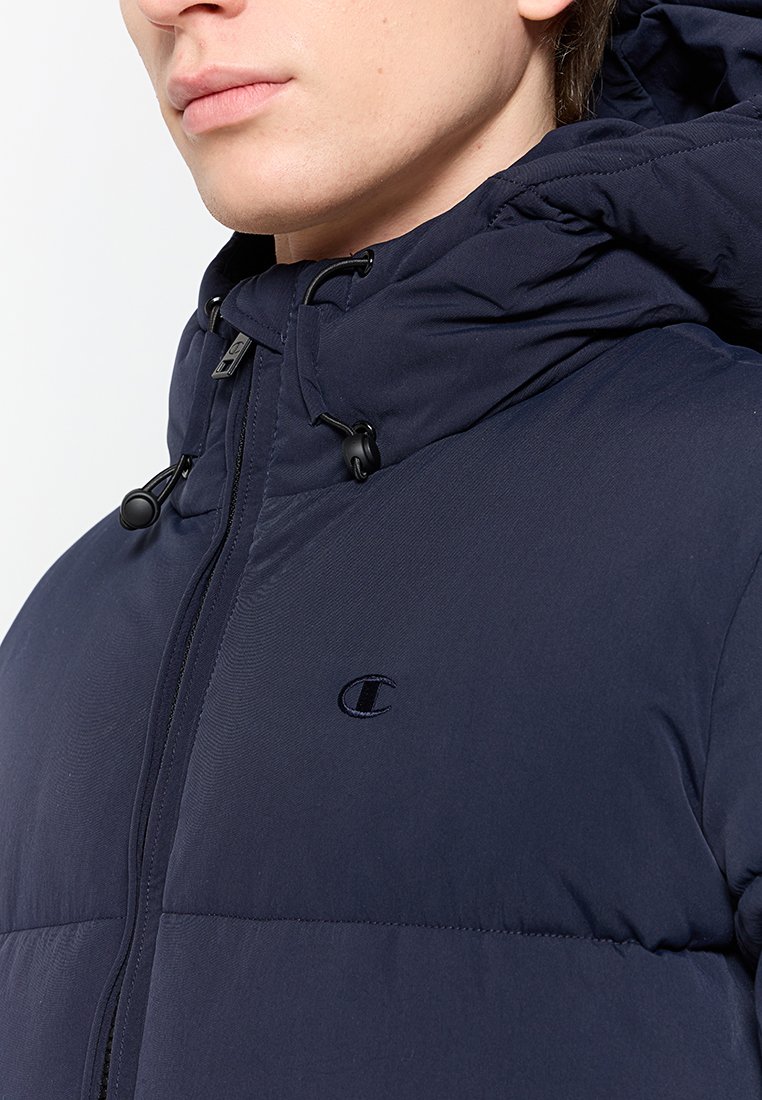 Veste rembourrée bleu marine avec capuche, dotée d'une fermeture éclair et d'un cordon de serrage. Logo sur la poitrine gauche, texture lisse et design utilitaire.