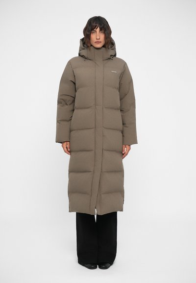 Langer gepolsterter Mantel in Taupe mit Kapuze, gerader Schnitt, gestepptem Muster und verdecktem Reißverschluss. Schwarze Hose und Schuhe.