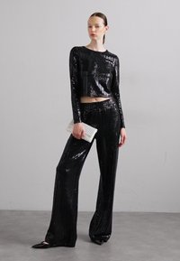 Mustmust tähendab musta sädelusecrop top ja sobivad laiad püksid, millel on läikiv viimistlus ja mis on kaunistatud valge tekstuuriga klambriga.