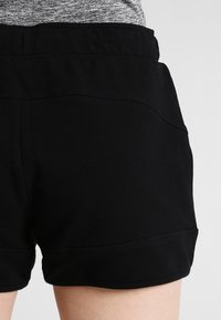 Svarta sportshorts tillverkade av ett slätt tyg, med elastisk midjeband och sydda detaljer längs sidorna.