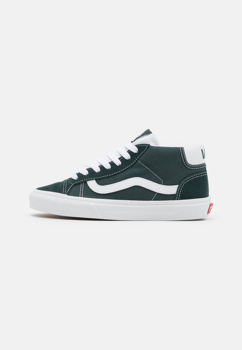 Baskets Vans noires montantes avec bande latérale blanche, lacets blancs et semelle blanche sur fond gris clair uni.