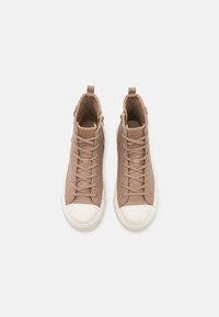Sneakers înaltbeige, confectionați din piele texturată, cu talpă din cauciuc alb. Caracteristici includ șireturi, fermoar lateral și un tab de prindere pe spate.
