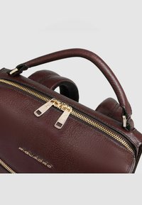 Borsa in pelle color bordeaux con finitura strutturata, doppia cerniera dorata e manico superiore. Dotata di cinturini regolabili per un trasporto versatile.