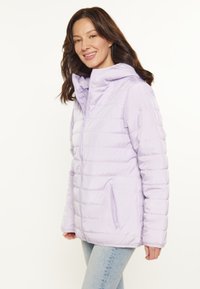 Jacheta puffer de culoare mov deschis, cu glugă, model cu cusături orizontale, buzunare cu fermoar și o textură netedă. Prezintă o închidere frontala cu fermoar.