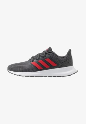 Chaussure de sport gris foncé avec des rayures rouges, des lacets noirs, une semelle blanche et une tige en mesh respirant, vue de côté sur fond blanc.