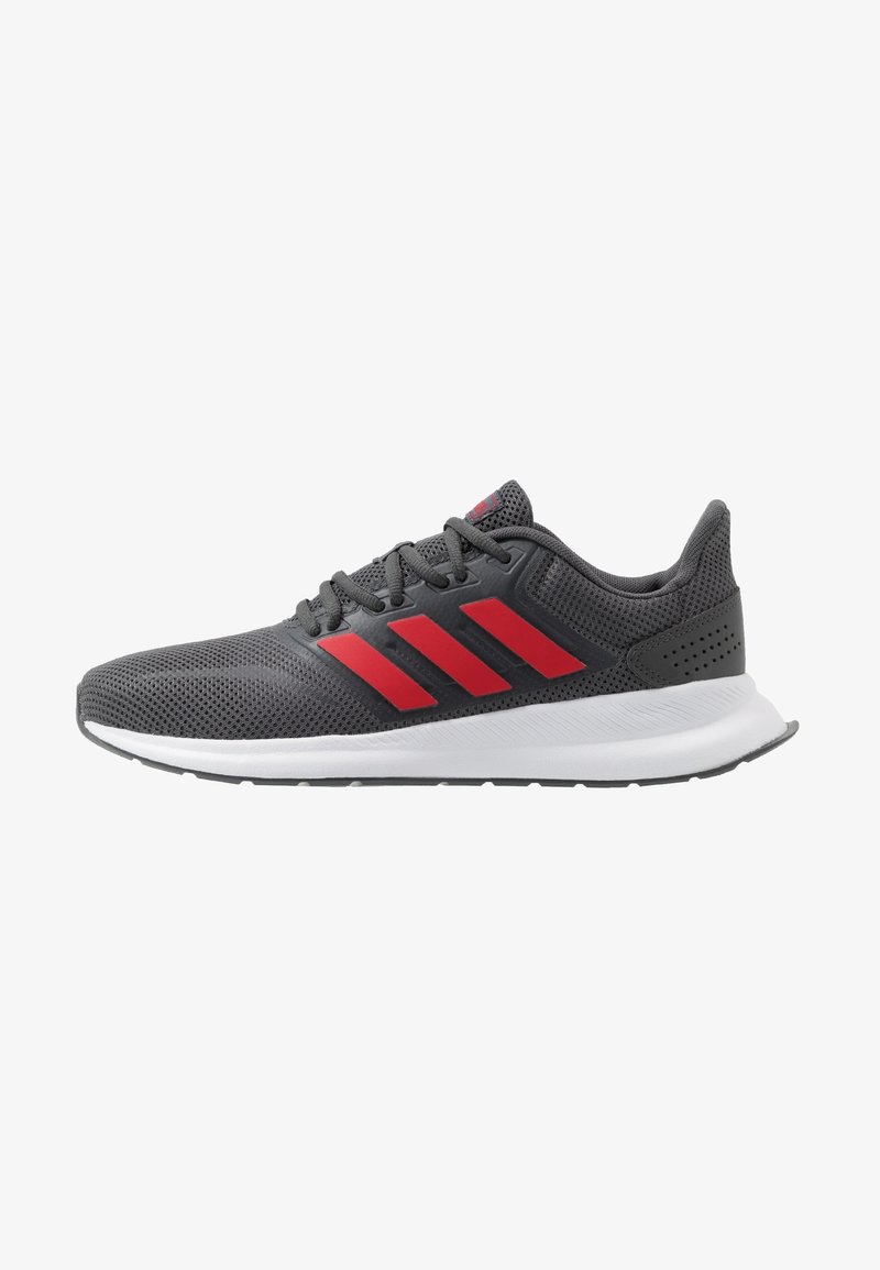 Chaussure de sport gris foncé avec des rayures rouges, des lacets noirs, une semelle blanche et une tige en mesh respirant, vue de côté sur fond blanc.