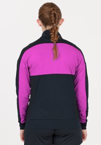 Svart och lila atletisk jacka med hög krage, långa ärmar och ett texturerat tyg med en färgblockdesign på övre ryggen.