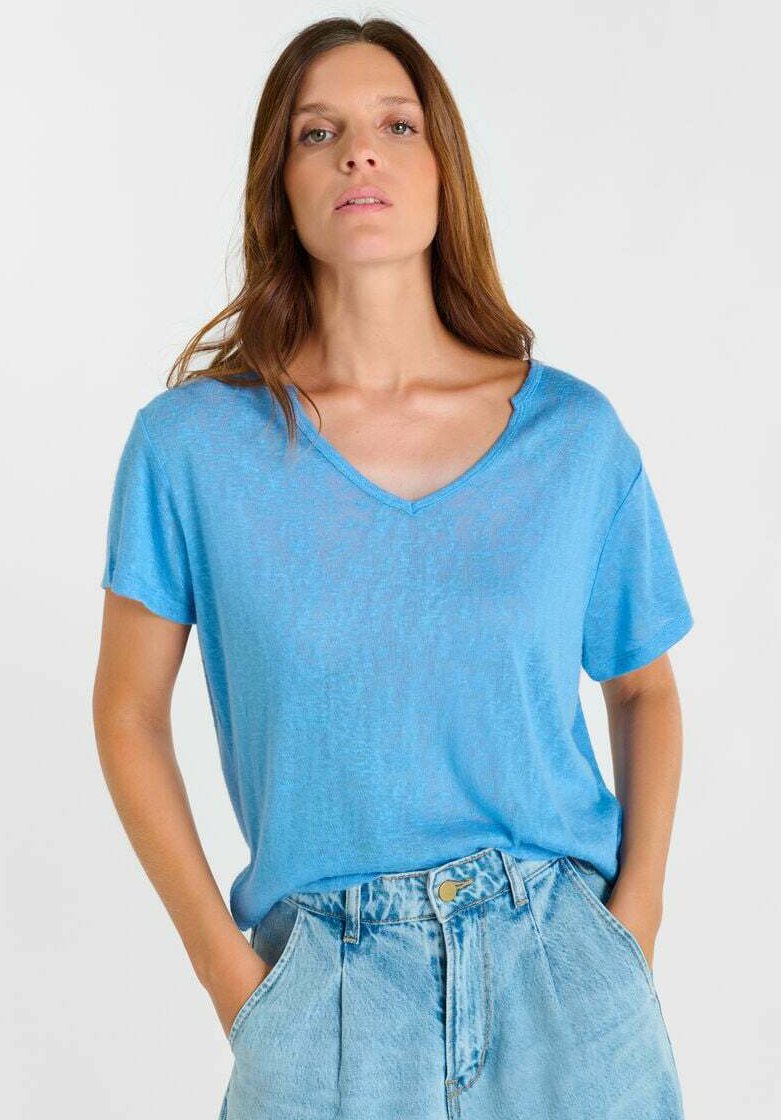 Lichtblauw T-shirt met korte mouwen, een V-hals en een losse pasvorm, gemaakt van een zachte, licht doorschijnende stof, gecombineerd met hoge taille denim shorts.