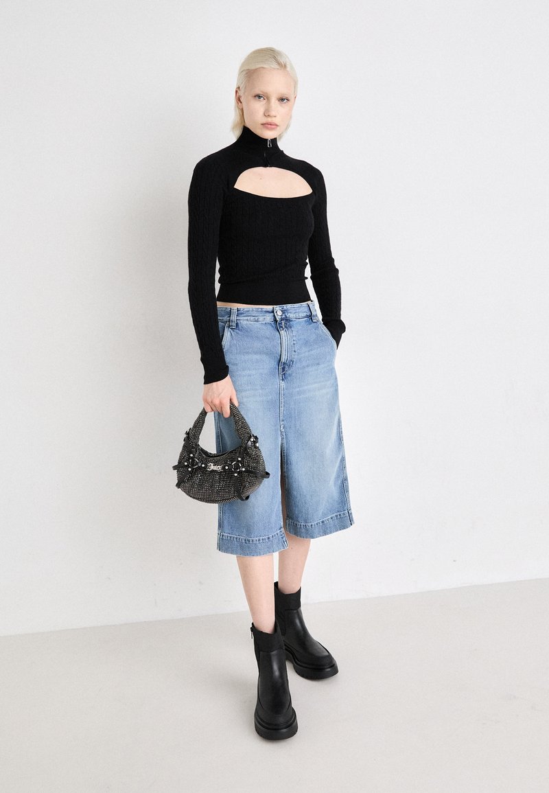 Top a maniche lunghe nero a coste con taglio, culotte in denim azzurro chiaro, stivaletti neri alla caviglia e una borsa nera testurizzata con decorazioni.