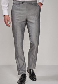 Pantaloni gri din stofă cu o textură netedă, picioare ușor conice și buzunare frontale, asortați cu pantofi din piele negri.