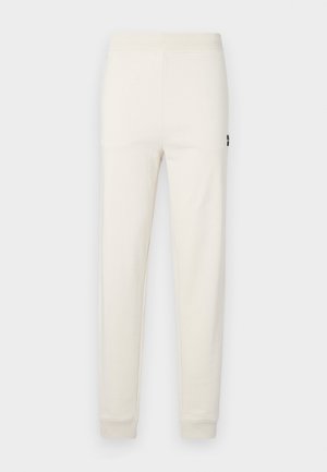 Cream-colored jogger pants made of soft cotton, featuring a stretchy waistband and fitted cuffs, with a small logo detail on the side.