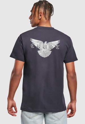 Mörkblå bomull t-shirt med en silverfärgad örn grafik och ordet "TRUST" i ett slitet typsnitt på baksidan. Korta ärmar, rundad hals.