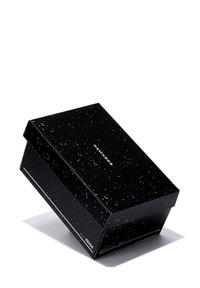 Cutie din carton negru cu un model punctat, cu un logo alb "HAWKERS" și textul "light by ZEISS", ușor înclinat pe un fundal alb.