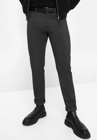 Grijze slim-fit broek van textuurstof, met een opgerolde zoom, gedragen met een zwarte riem en leren enkellaarsjes.