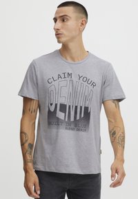 Grå bomull T-skjorte med en dristig grafisk trykk med ordene "CLAIM YOUR DENIM" og "BUILT IN BLUE." Vanlig passform med rund hals.
