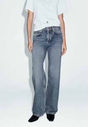 Blue wide-leg jeans made of denim with a faded wash, featuring a high waist, five-pocket design, and subtle stitching details.