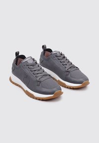 Zapatillas deportivas grises con parte superior de malla, acentos texturizados, media suela blanca y suela de goma. Incluyen cordones y un tirador.